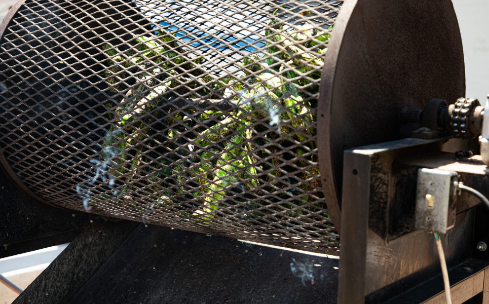 Green chile roasts inside a roaster.