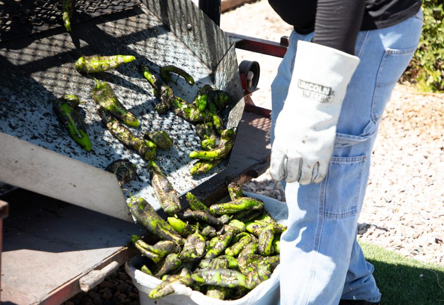 Green chile slides out of the roaster and into a bucket.