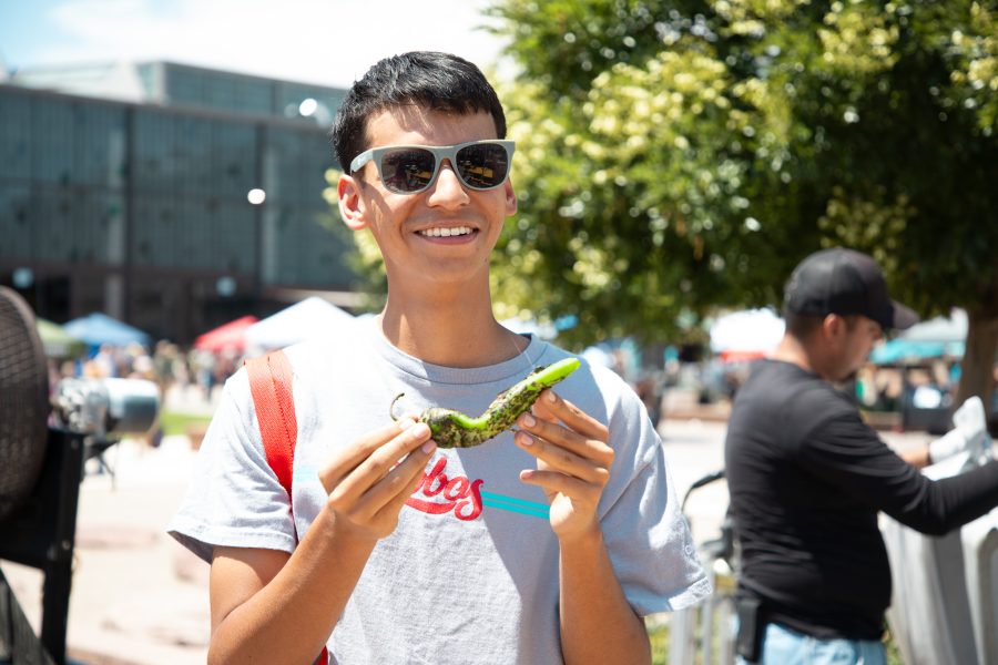A student smiles while holding a freshly-roasted green chile.