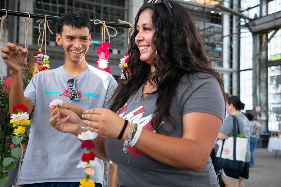 Two students smile as they assemble flower crowns inside the Rail Yards Market.