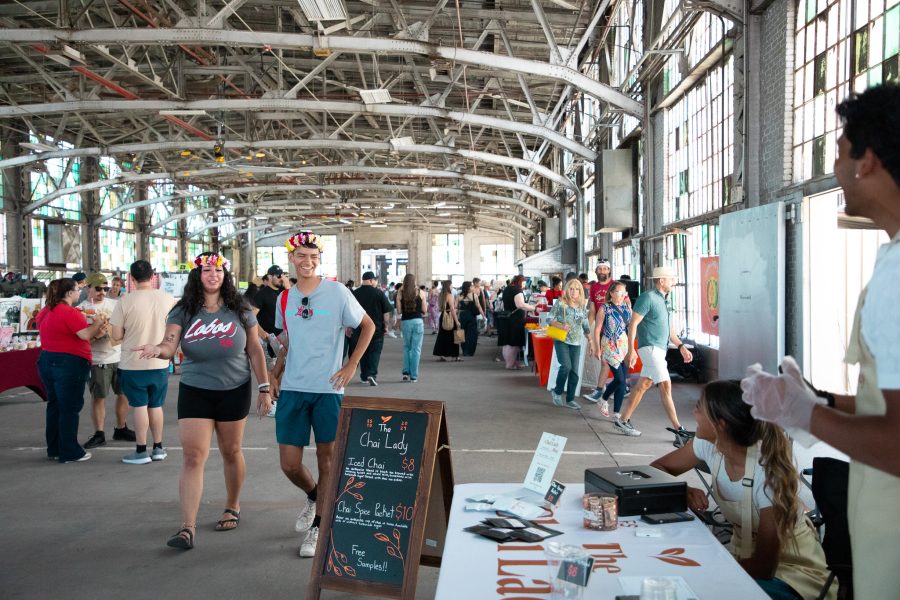 Two smiling students approach a chai booth inside the Rail Yards Market.