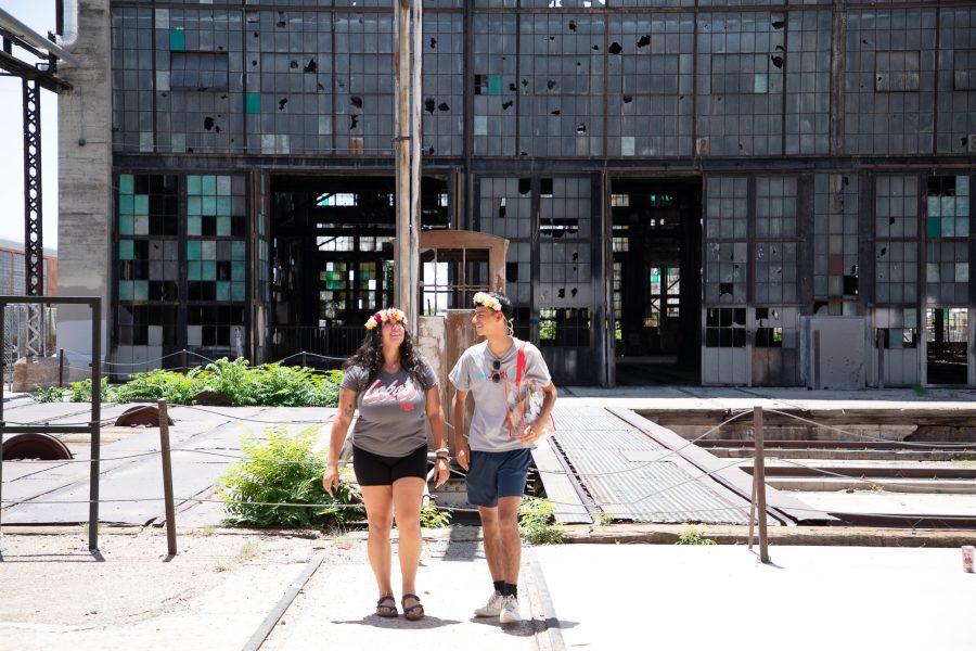 Two smiling students walk into the Rail Yards Market with the green-tinted windows behind them.