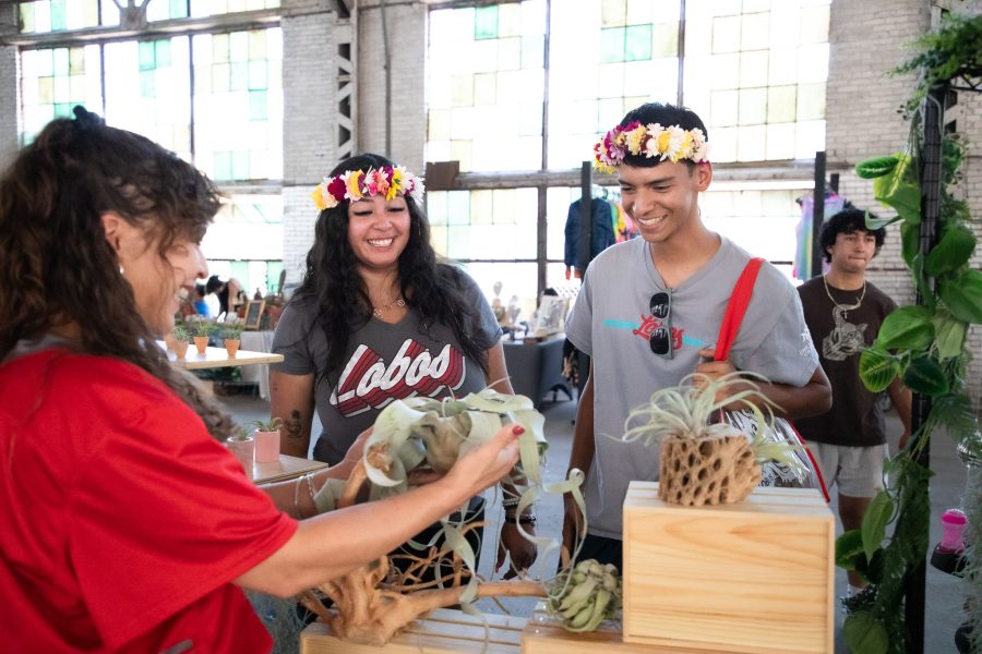 Two students smile as a vendor presents a plant to them.