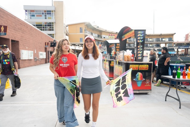 Two students dressed in UNM merchandise walk through the concourse at a New Mexico United game.