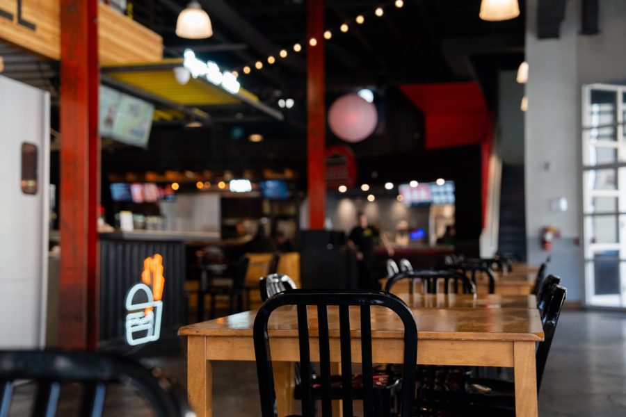 A large seating area is seen with string lights and neon signs in the food hall.