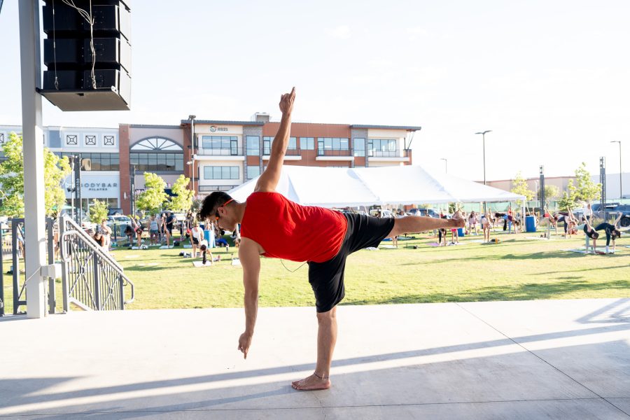 A yoga instructor demonstrates a pose in front of a crowd.