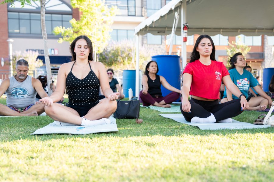 Two UNM students do the lotus pose with their eyes closed.