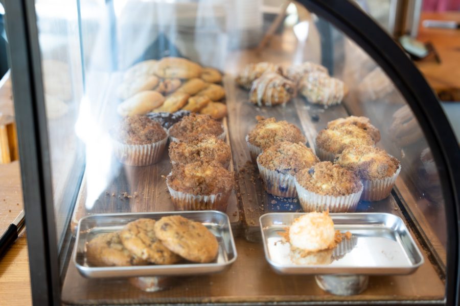 Pastries including cookies, muffins and scones are inside a glass display case.