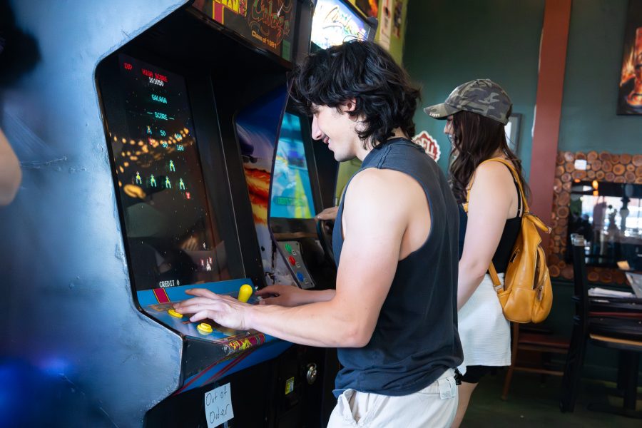 Two students play arcade games inside Trail Rider Pizza.