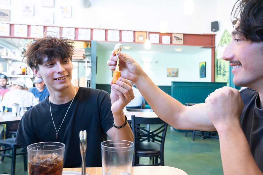 Two students split a mozzarella stick, watching the cheese pull.
