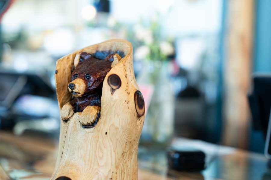A carving of a bear peaking out of a log is displayed inside Trail Rider Pizza.