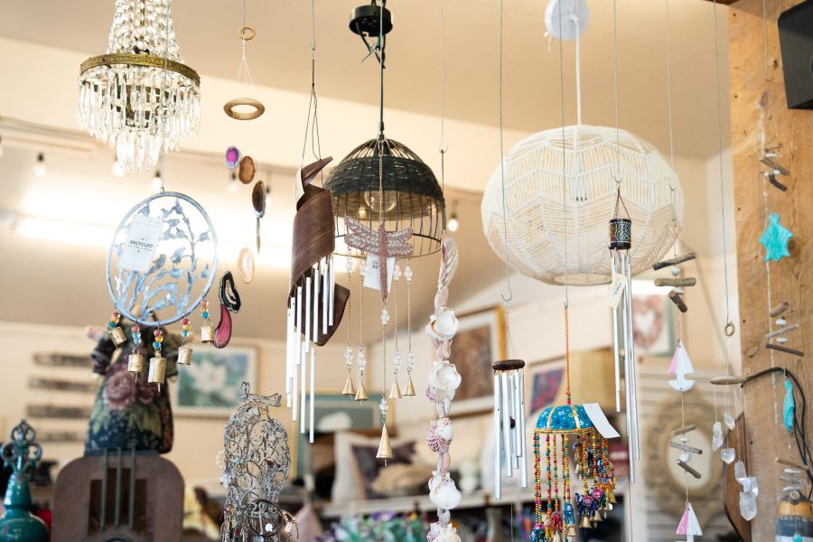 Many hanging fixtures including wind chimes and lights are displayed inside of Hey Mavis! Thrift Store.