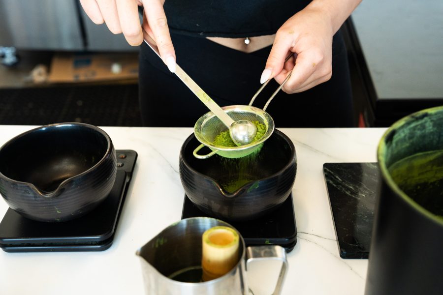 A Homebody barista sifts matcha powder.