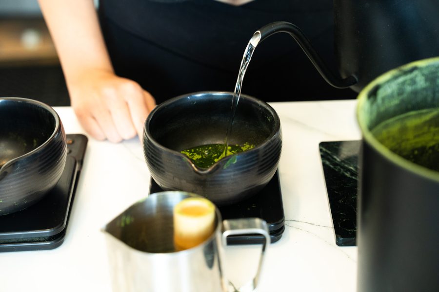 A Homebody barista pours hot water into vividly green matcha powder.