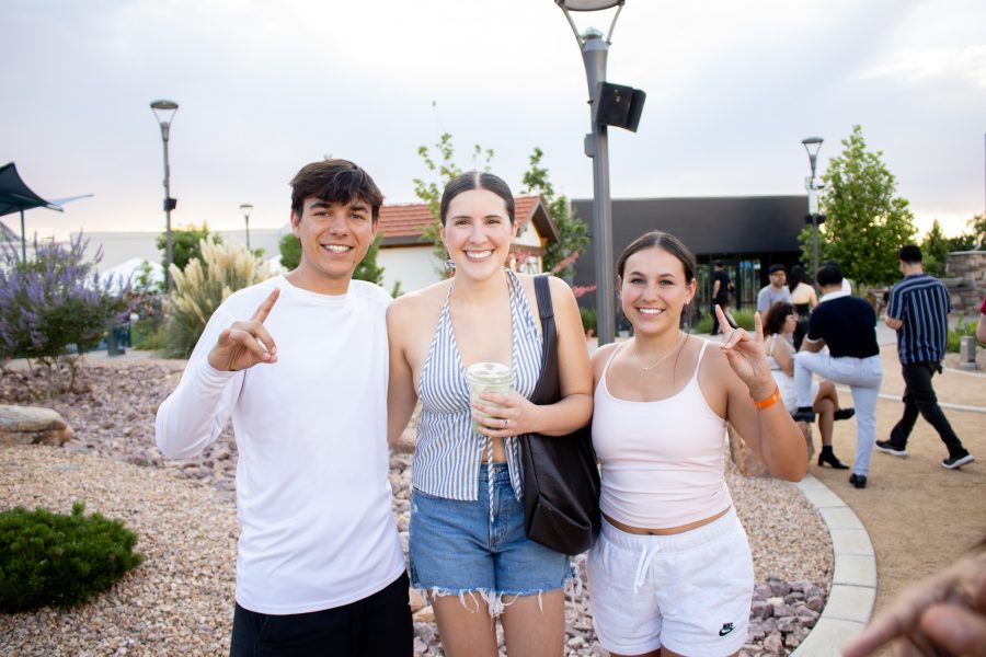 Three UNM students hold up the Lobo hand symbol while at the night market at Winrock.