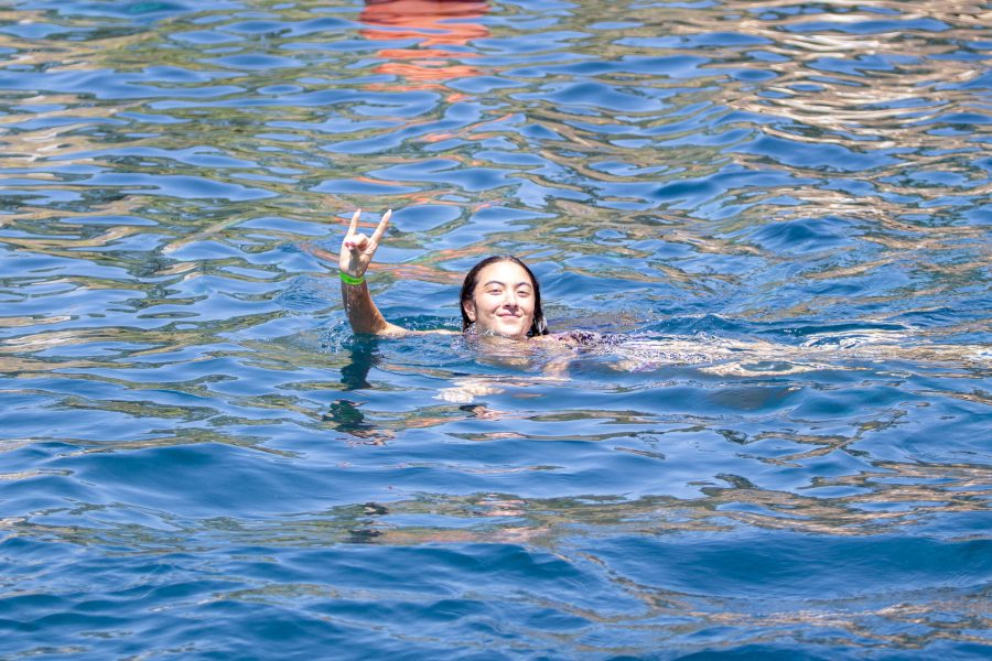 A student holds up the Lobo hand symbol while swimming.
